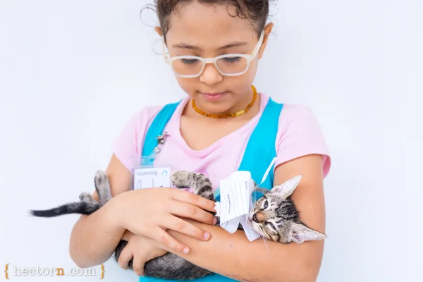 A young child holding a kitten